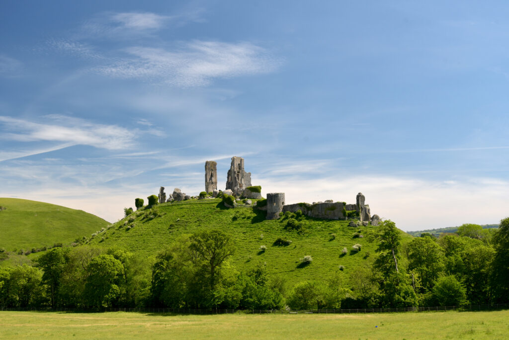 The historic landmark outline of Corfe Castle above the fields i