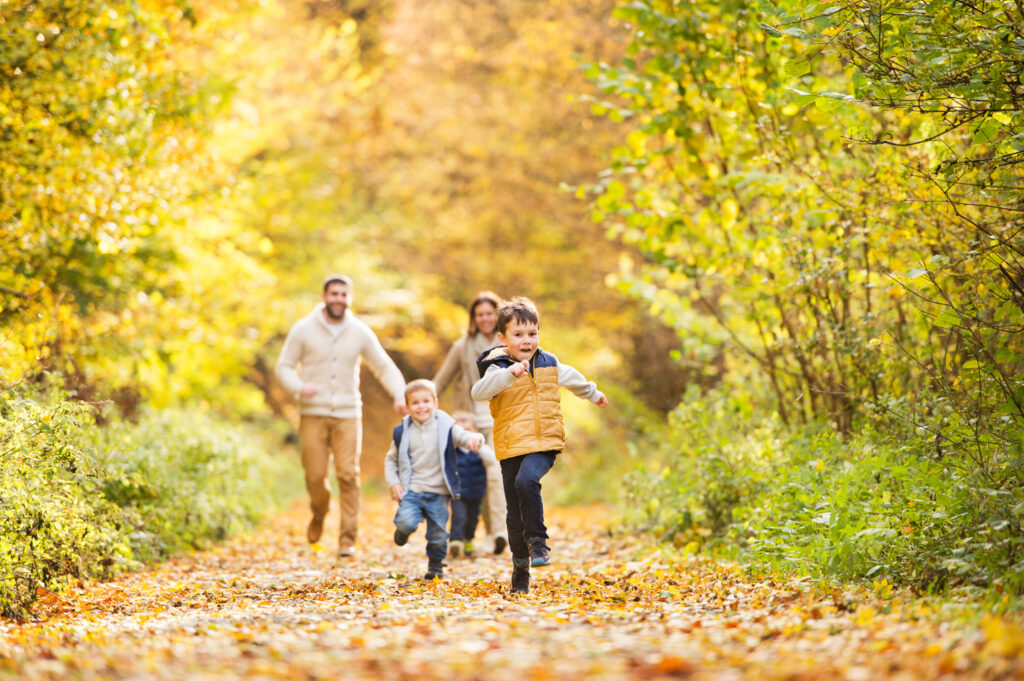 Beautiful young family on a walk in autumn forest.