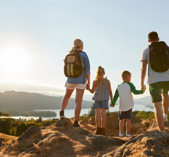 Rear View Of Family Standing At Top Of Hill On Hike Through Countryside In Lake District UK