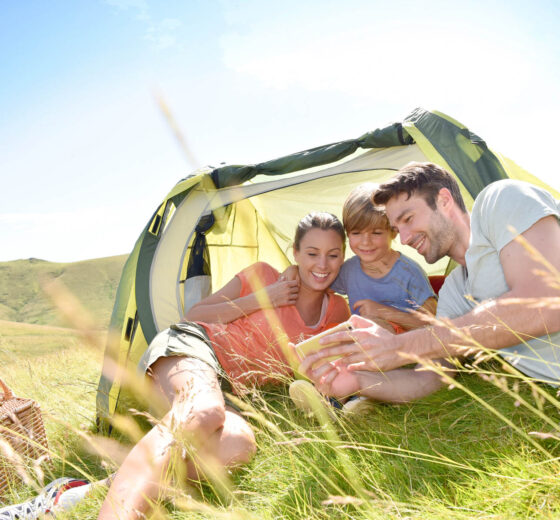 Family in camping tent playing with smartphone