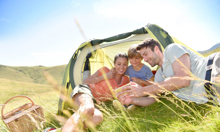 Family in camping tent playing with smartphone