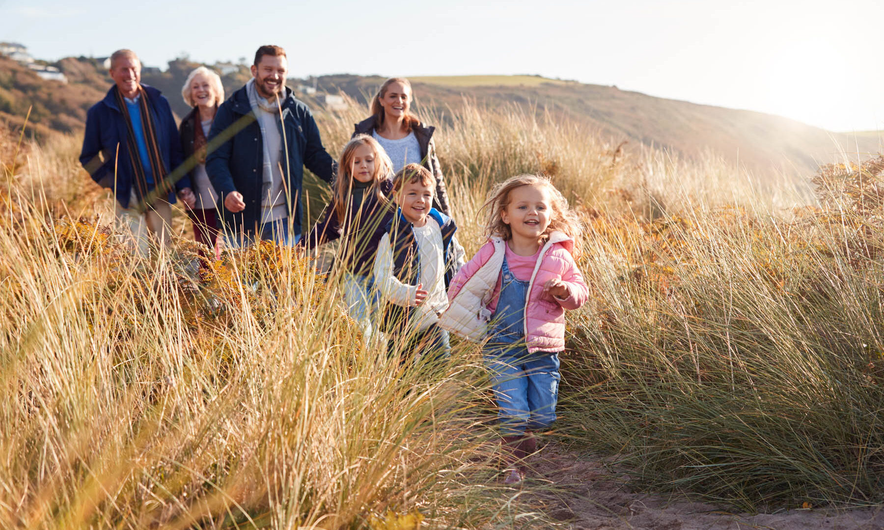 Multi-Generation Family Walking Along Path Through Sand Dunes Together